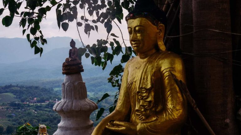a statue of a person sitting on top of a white and white pillar
