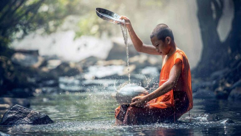 a boy in a robe pouring water into a bowl